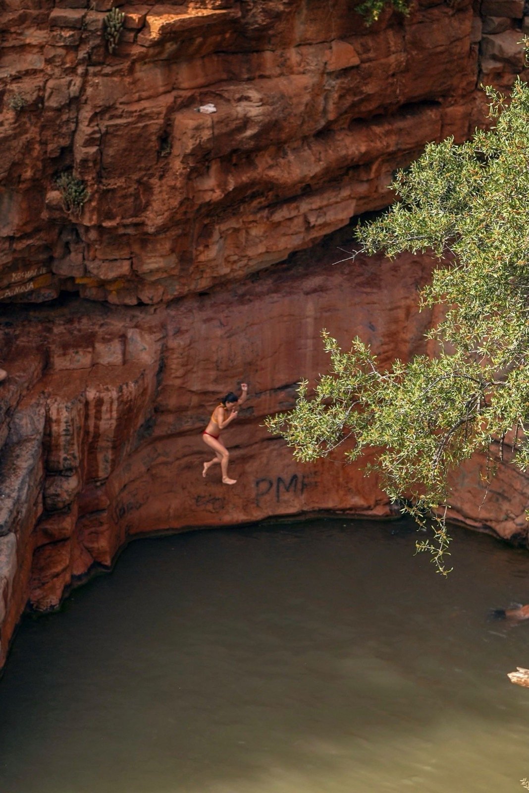 Salto desde la pared de roca roja a la piscina profunda de Paradise Valley