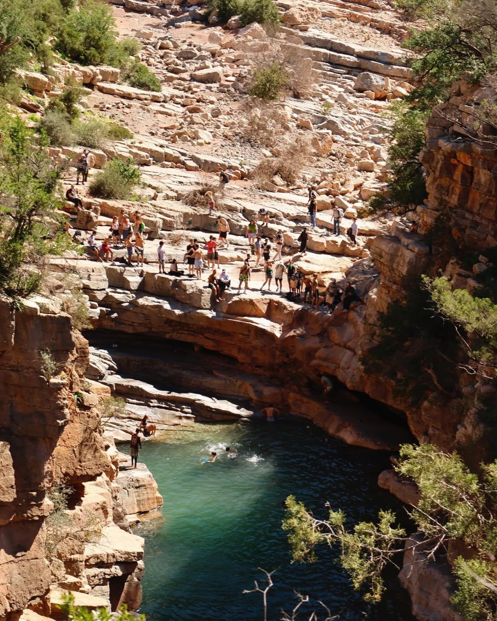 Vasque profonde et verte dans la roche à Paradise Valley, avec des personnes sur les corniches