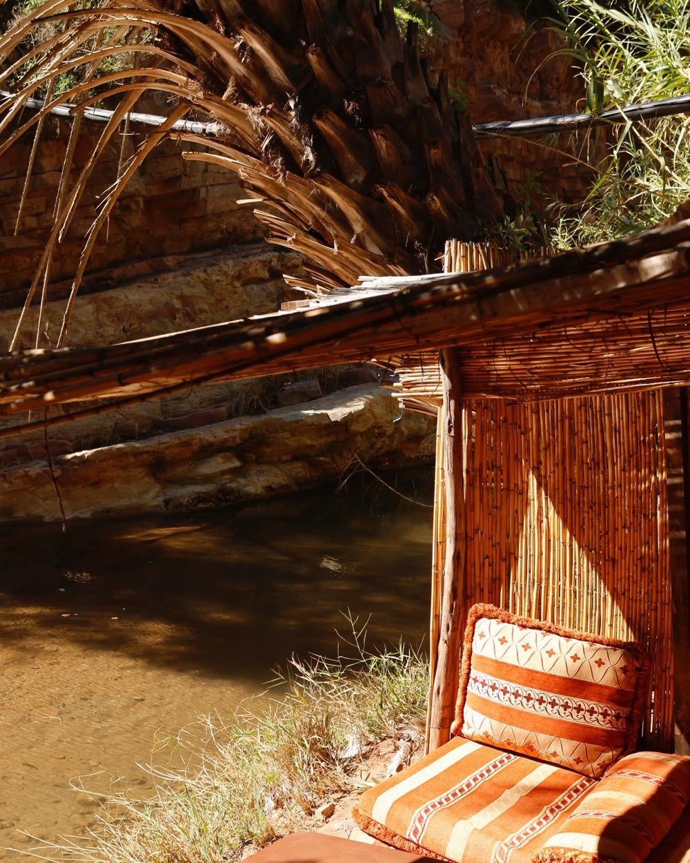 Coin ombragé en roseaux avec des coussins au bord de l'eau à Paradise Valley