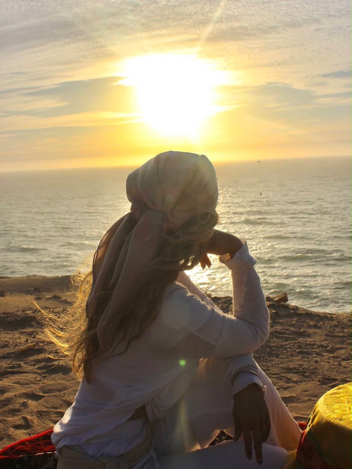 Mujer viendo la puesta de sol sobre el Atlántico desde las dunas