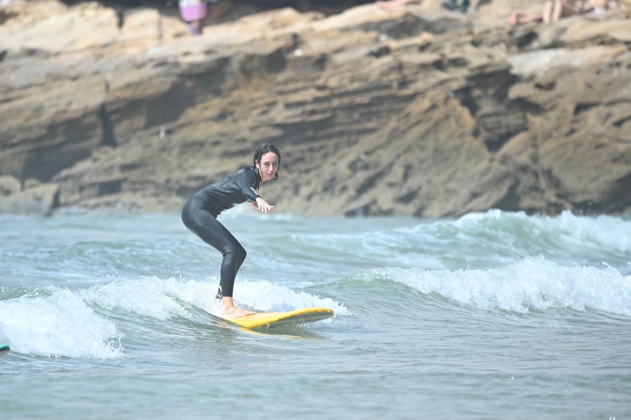 Beginner surfer standing up on a yellow board in the whitewater